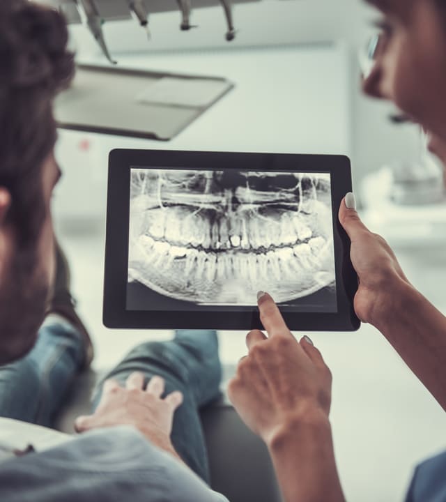 Young patient and female dentist are looking at teeth X ray image on a digital tablet