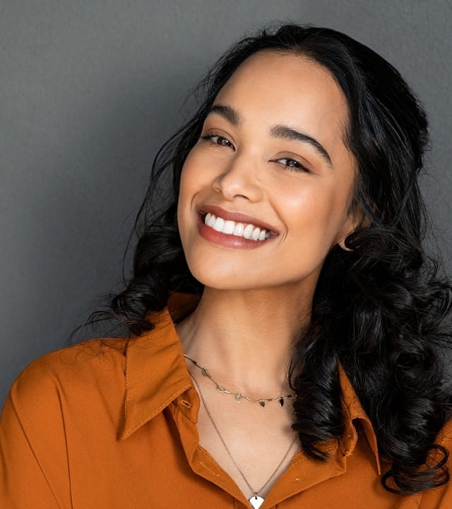 Close up face of young woman with beautiful white smile isolated on grey wall