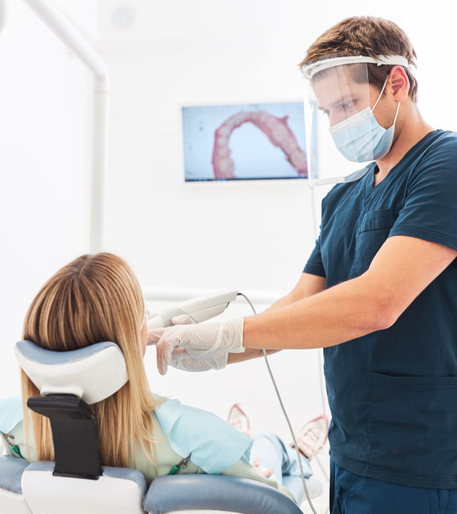 The dentist scans the patient's teeth with an intraoral camera.