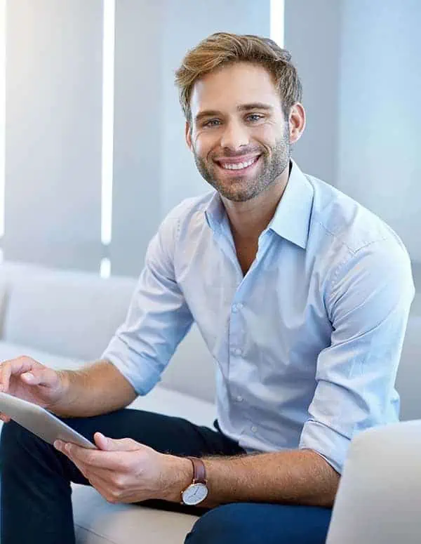 Young man sitting in an office sofa with an iPad in his hands
