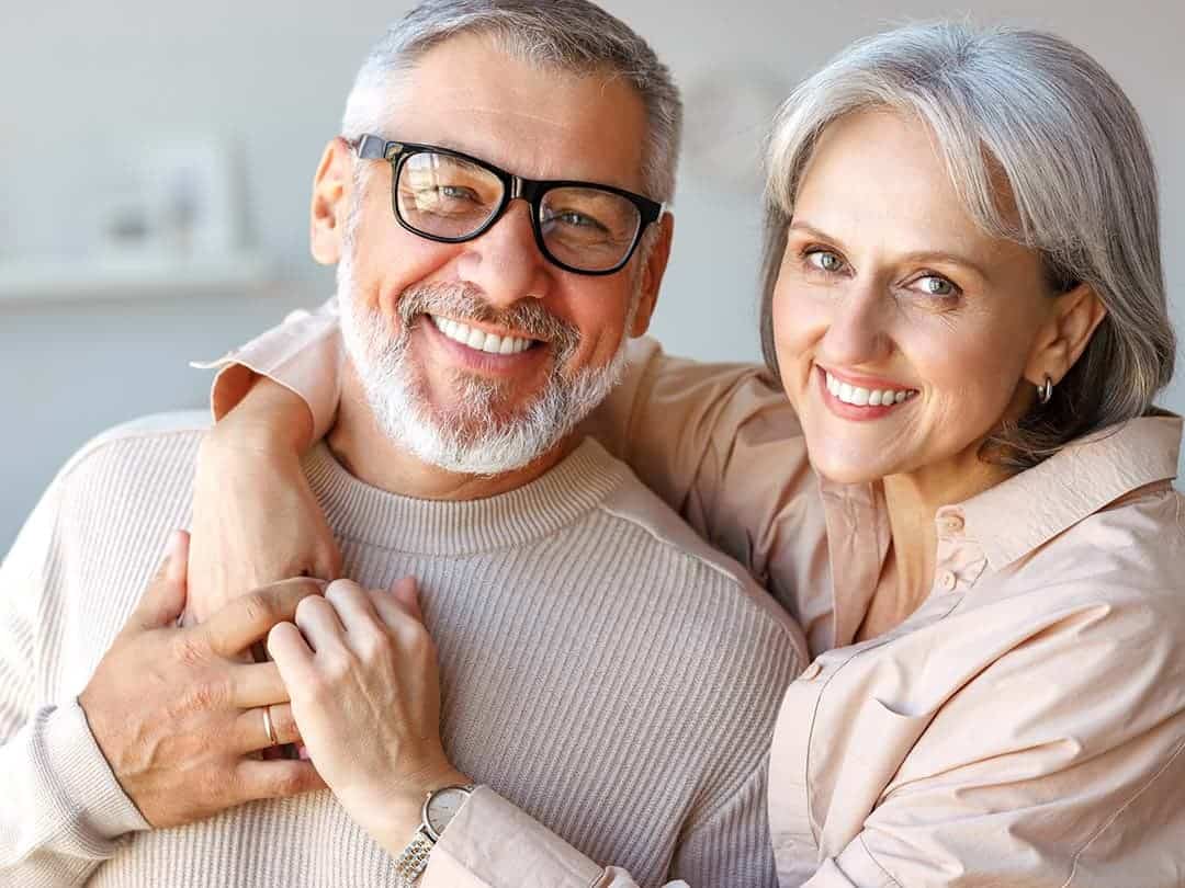 Elderly couple in their home smiling and<br />
embracing each other