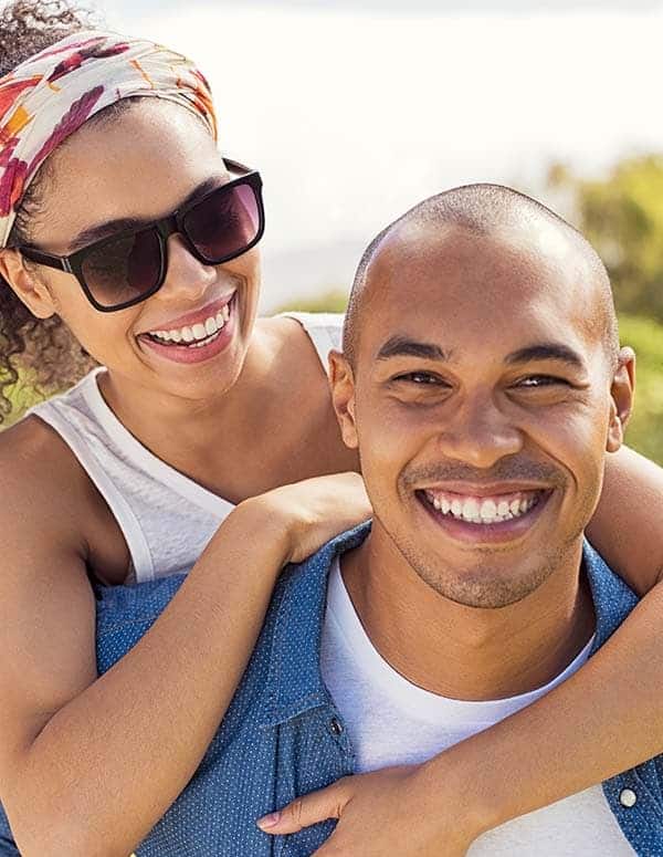 Close-up image of a young couple in nature smiling at the camera.